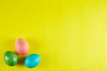 Fototapeta na wymiar Bunch of blank painted Easter eggs of different pastel color on bright yellow paper background with a lot of copy space for text. Top view, flat lay, close up.