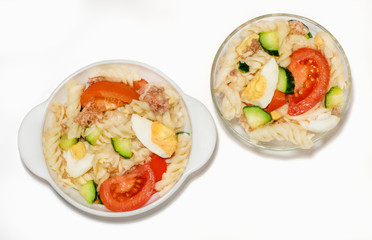 Tuna salad isolated on white background. Two portions. Top view. Tuna, pasta, eggs, cucumbers, tomatoes, onions. Traditional salad.