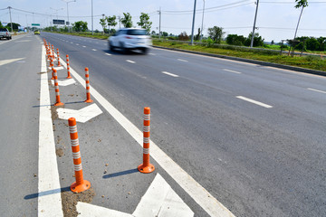 Orange traffic pole or flexible traffic bollard on asphalt road for crossroad.