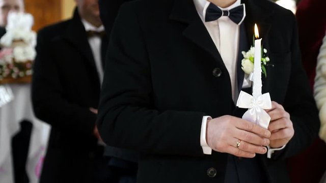 Groom holds a candle in the church. Christianity wedding ceremony.
