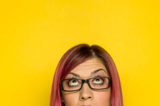 Half portrait of young woman with pink hair and questionable expresion on yellow background