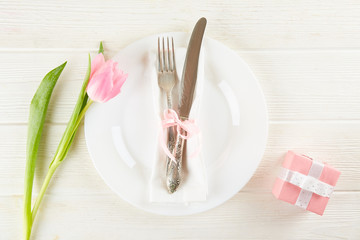 Table setting arrangement in minimal style with easter spring holiday attributes, fork, knife and napkin. Background, copy space, close up, flat lay, top view.