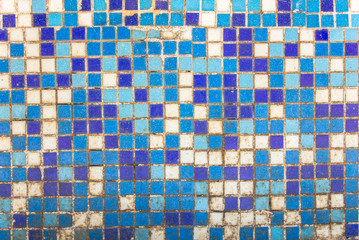 old dirty wall of small blue and white ceramic tiles. rough surface texture