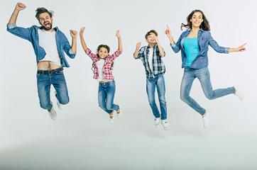 Excited and happy family in casual clothes are jumping together and shouting isolated in white