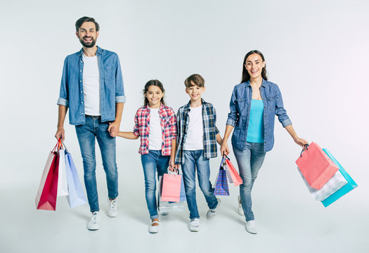 Big beautiful happy and excited family walking together after shopping in the mall with purchases in hands isolated on white