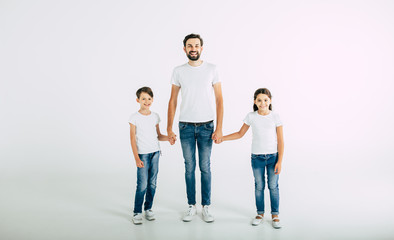 Fototapeta premium Handsome young father holds him son and daughter to hands isolated on white
