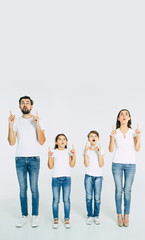 Obraz premium Beautiful family standing in line and pointing up and shouting isolated on white background