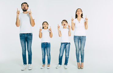 Beautiful family standing in line and pointing up and shouting isolated on white background