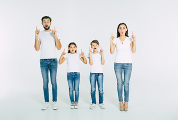 Fototapeta premium Beautiful family standing in line and pointing up and shouting isolated on white background