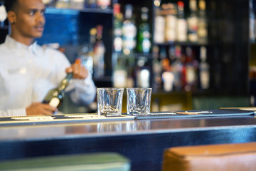 Bartender man pours whiskey to the client of the hotel bar. The concept of service.