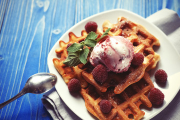 Plate of belgian waffles with ice cream  and fresh berries over blue wooden background