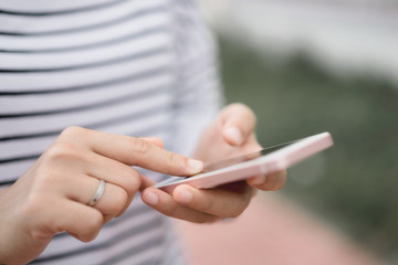 Close up woman hand hold using smart phone on outdoor park street background.