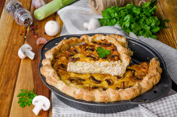 Quiche on puff pastry with leek, meat and mushrooms. Rustic style.