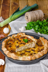 Quiche on puff pastry with leek, meat and mushrooms. Rustic style.