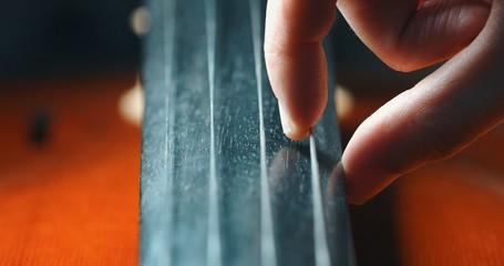 Macro close up of master artisan luthier pulling a string of a handmade violin or cello