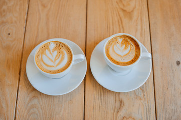 Two white cups with espresso on wood table