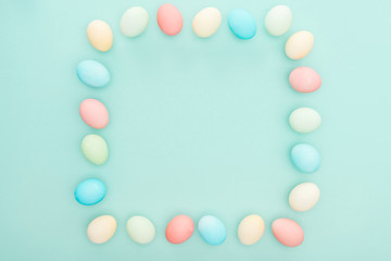 top view of empty frame made of pastel easter eggs isolated on blue