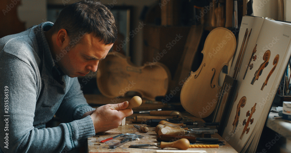 Poster Macro close up of professional master artisan luthier painstaking detailed work on wood violin in a workshop