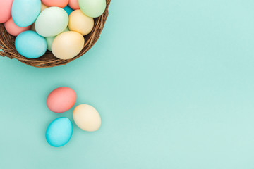 Naklejka na ściany i meble top view of traditional pastel easter eggs in wicker basket isolated on blue with copy space
