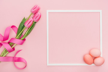 top view of pink tulips with ribbon and easter eggs with frame isolated on pink