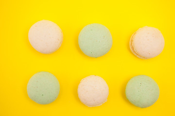 Top view of Peach and green tee macaroons in rows over yellow background