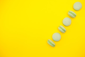 Top view row of green french macaroons over yellow background