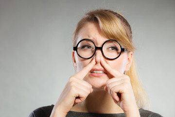 Girl pinches her nose because of stench stink.