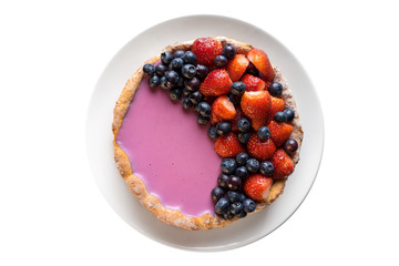 Homemade baked berry pie cake with strawberry and blueberry on white plate on white background flat lay top view
