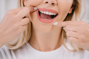 cropped view of woman flossing teeth with dental floss