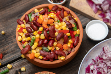 Mixture of vegetables, dried boletus mushrooms, sliced potato, red onion sliced and whole on a cutting board and spices, on old rustic wooden table.