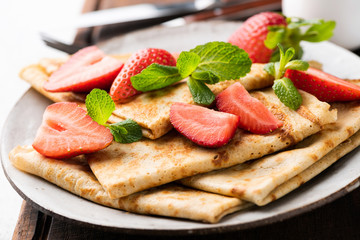 Crepes with strawberry or thin pancakes Blini. Closeup view