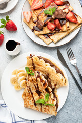 Crepes with chocolate, banana and strawberry. Top view. Tasty European or French style breakfast, table top view