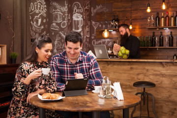 Happy couple using digital tablet while having coffee at restaurant