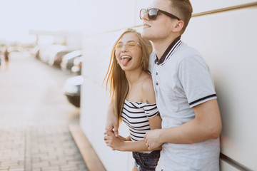 Hipster young loving couple in fashionable sun glasses walking together, embrace each other, hugging and having fun in summer. Urban, love, happiness concept