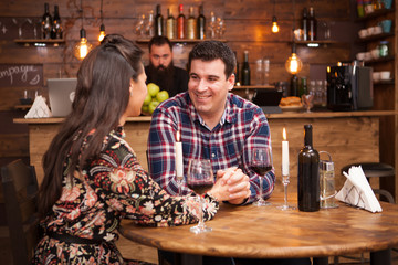 Couple drinking red wine and sharing a beautiful moment in a hipster pub.