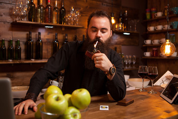 Bearded handsome young bartender lighting his cigarette.