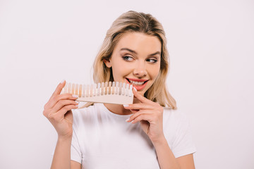 Naklejka premium beautiful smiling woman holding teeth color palette isolated on white, teeth whitening concept
