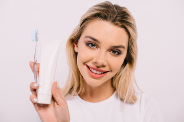 beautiful smiling woman holding toothbrush and toothpaste with copy space isolated on white