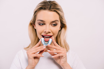 beautiful woman putting on orthodontic trainer dental braces isolated on white