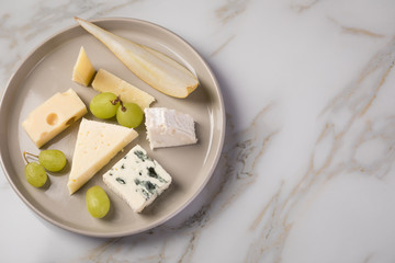 Käseteller mit Edamer, Parmesan, Blauschimmel Käse und Ziegenkäse an Birne und Trauben auf...