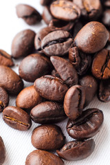 Obraz premium Zamknij się ciemne palone ziarna kawy na białej bawełnianej tkaninie i białym tle papieru filtracyjnego w naturalnym świetle