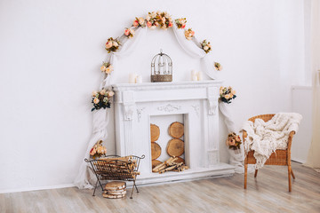 Interior with a beautiful decorative white fireplace and wood. Armchair by a decorative fireplace