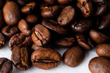 Close up dark roasted coffee beans on white cotton fabric and white filter paper  background in natural light 