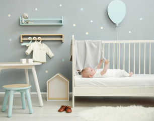 Adorable baby in the white outfit in the nursery