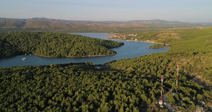Mediterranean river, C4k aerial, tracking, drone shot, of a boat on morinje lake, on the croatian shore, overlooking the Jadrtovac village, on a sunny, summer evening, in Croatia