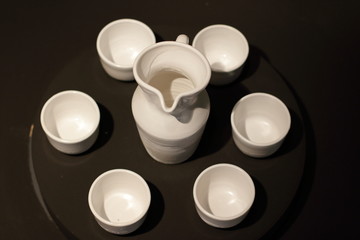 white ceramic set for wine on black background, jug and six glasses