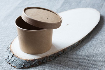 Disposable kraft paper cup on a wooden board.