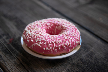 Homemade pink glazed donuts on old wooden table