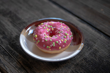 Homemade pink glazed donuts on old wooden table