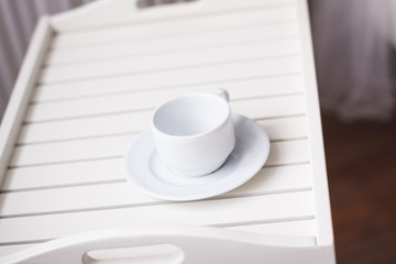 White mug with a saucer on a wooden tray